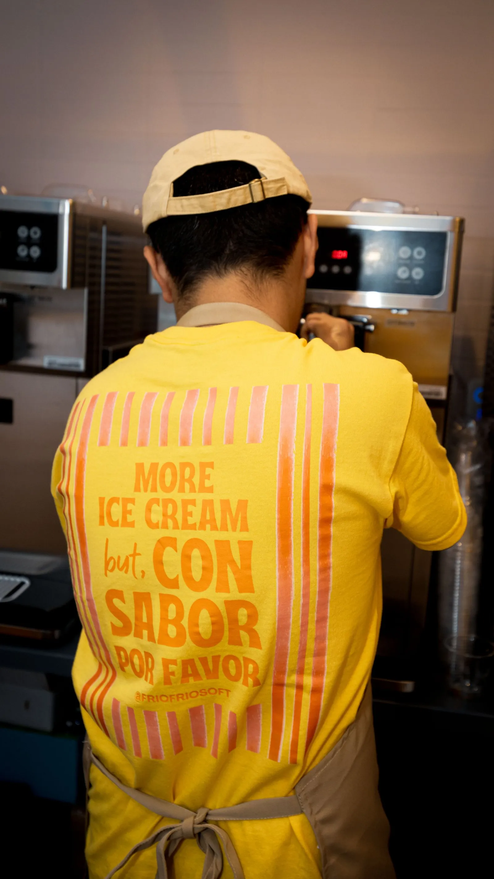 Frío Frío team member in a “More ice cream but con sabor por favor” shirt at the soft serve machine